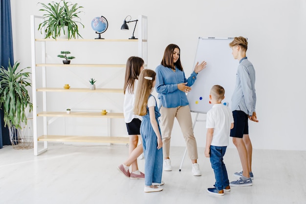 Explicando a lição e usando o quadro Grupo de alunos de crianças de diferentes idades em sala de aula na escola com o conceito de aprendizagem do professor