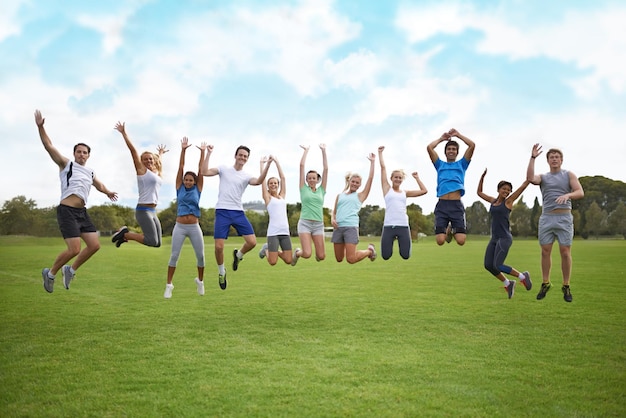 Explodindo de vitalidade Um grupo de jovens pulando no ar em um campo esportivo