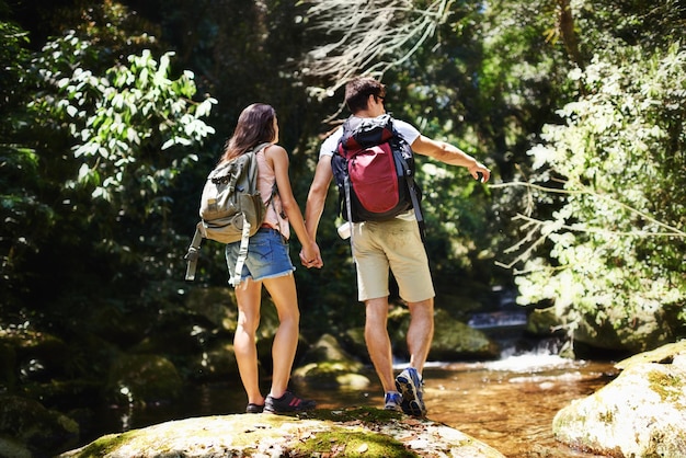 Foto exploradores del bosque vista trasera de una joven pareja caminando por el bosque