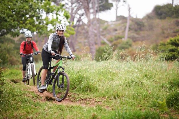 Explorando los caminos menos transitados Un par de jóvenes ciclistas disfrutando del aire libre y manteniéndose en forma en bicicleta de montaña