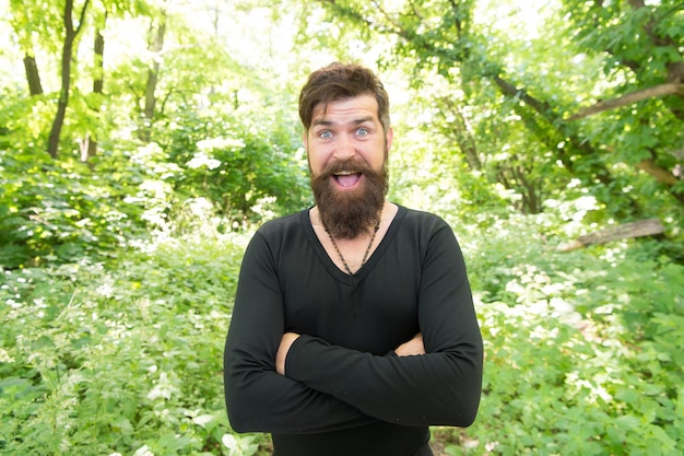 Explorando la naturaleza Hombre guapo con barba y bigote en la naturaleza Brutalidad del concepto de selva Temporada de calor de verano Naturaleza salvaje Hombre barbudo hipster fondo de follaje brillante Chico relajarse en el bosque