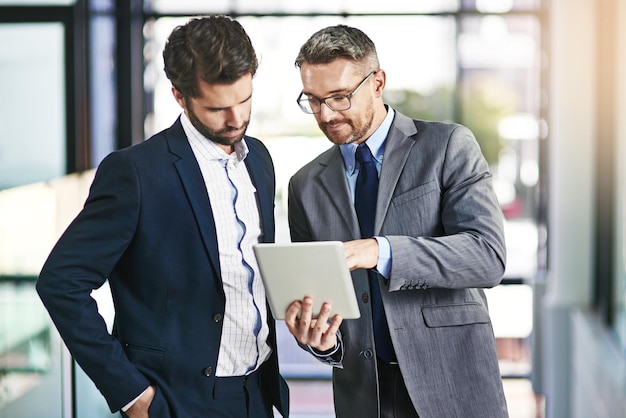 Explorando novos mercados para expandir seus negócios Foto recortada de dois empresários trabalhando juntos em um tablet digital em um escritório