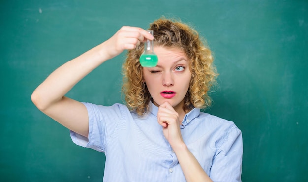 Explore la química. Lección de química. Laboratorio de quimica. Interesante y fascinante. Profesora realizando experimentos con bulbo y líquido. Chica observando fondo de pizarra de reacción química.