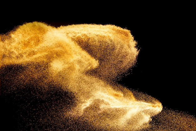 Explosão de areia dourada isolada no fundo preto. Nuvem de areia abstrata. Onda de mosca areia no ar.