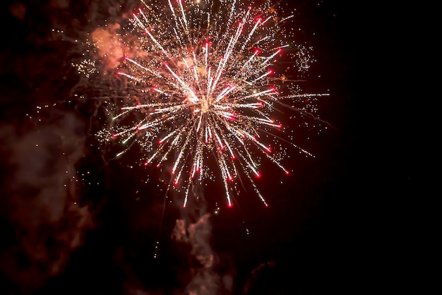 Explosão de fogos de artifício de belas estrelas espirra faíscas e linhas brilhantes de luzes com fumaça de cor vermelha e amarela contra o céu negro