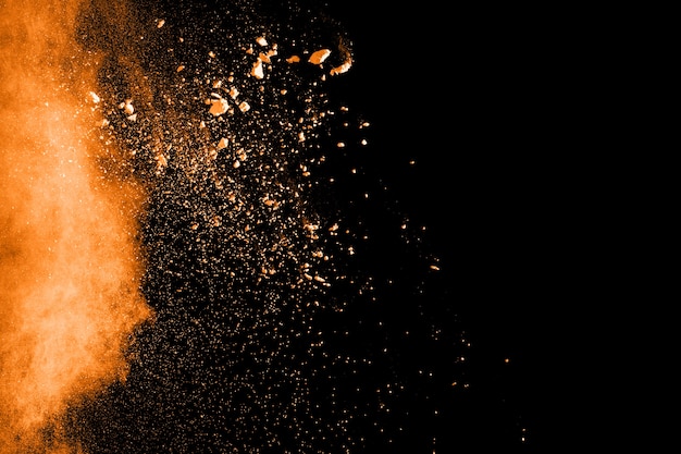 Explosão de pó laranja em fundo preto.
