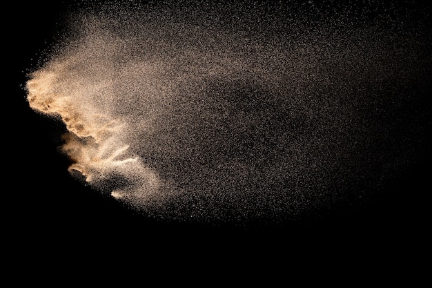 Foto explosión de arena dorada aislada sobre fondo negro.