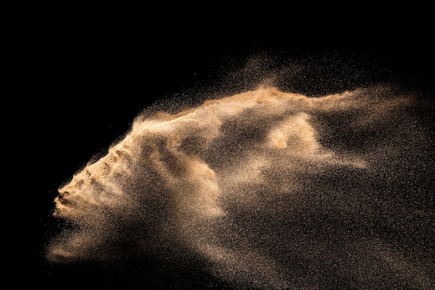 Foto explosión de arena dorada aislada sobre fondo negro.