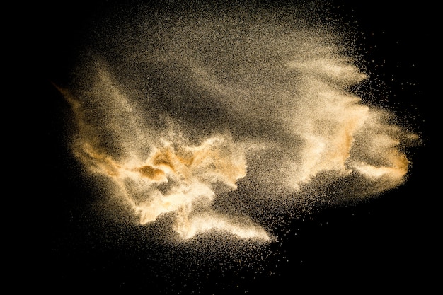 Foto explosión de arena de río seco aislado sobre fondo negro. nube de arena abstracta salpicaduras de arena de color marrón sobre fondo oscuro.