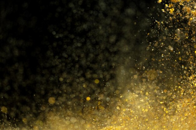 Explosion metallic gold glitter sparkle Golden Glitter powder spark blink celebrate blur foil explode in air fly throw gold glitters particle Black background isolated selective focus Blur bokeh