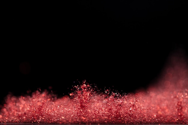 Explosion metallisches rotes Glitter funkeln Rose Glitter Pulver Funken blinken feiern verschwommen Folie explodieren in der Luft fliegen werfen rote Glitter Partikel Schwarzer Hintergrund isolierter selektiver Fokus Blur Bokeh