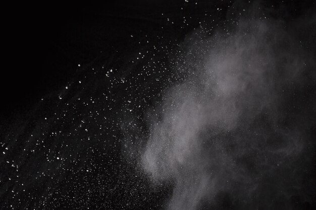 Foto explosión de polvo blanco sobre fondo negro. nube de color el polvo colorido estalla.
