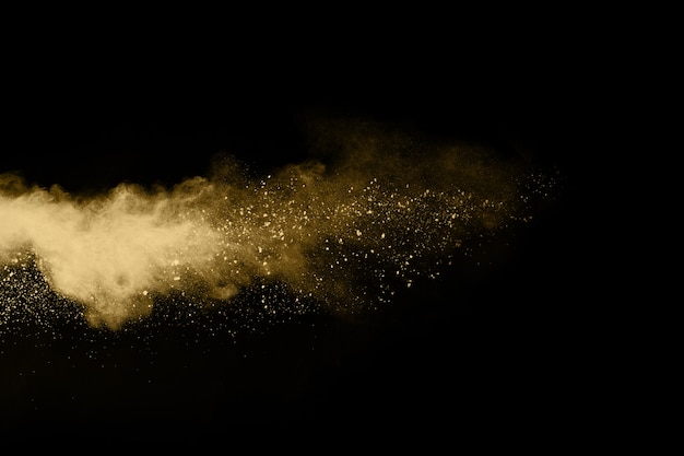 Explosión de polvo de oro sobre fondo negro. Congelar el movimiento.