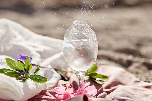 Explosion von Tonic-Cocktail in Weinglas am Strand mit Blumen Sommercocktail Zarte Seidenmaterialien und Bokeh-Hintergrund Erfrischendes Sommerkonzept Hochwertiges Foto