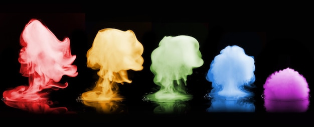 Foto explosões de fumaça em cores diferentes isoladas na superfície preta