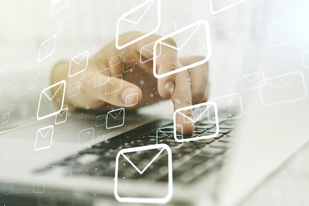 Exposição dupla de envelopes postais holograma com mãos digitando em laptop em fundo conceito de correio eletrônico e spam