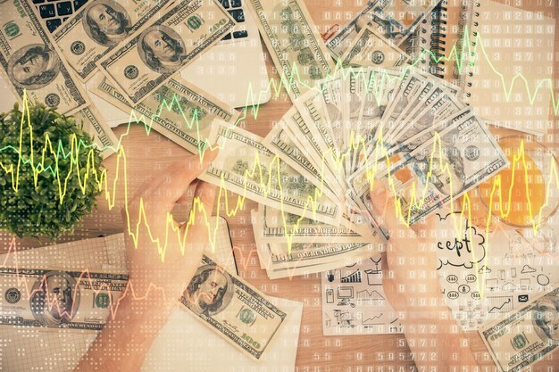 Foto exposição múltipla de holograma de desenho de gráfico financeiro e notas de dólares americanos e conceito de análise de mãos de homem
