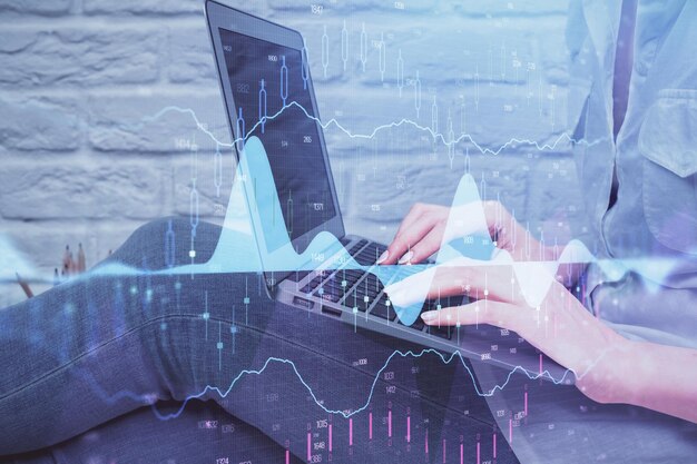 Exposição múltipla de mãos de mulher digitando no computador e desenho de holograma de gráfico forex Conceito de análise do mercado de ações