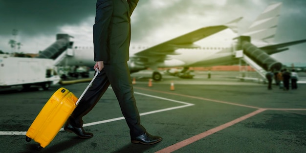 Exposición doble del hombre de negocios que camina en el campo del aeropuerto