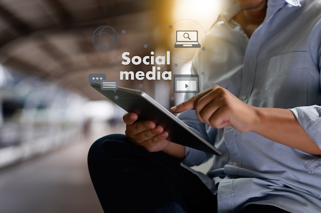 Foto exposición doble de la mano del hombre de negocios que trabaja en la computadora portátil en el escritorio de madera con el diagrama de red de medios sociales