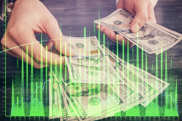 Exposición múltiple del holograma de dibujo de gráficos financieros y billetes de dólares estadounidenses y concepto de análisis de manos de hombre