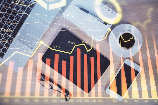 Exposición múltiple del holograma gráfico de forex sobre el escritorio con el teléfono Vista superior Concepto de plataforma de comercio móvil