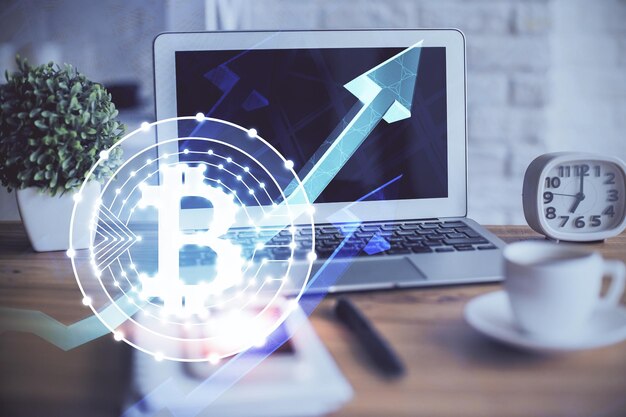 Exposición múltiple del holograma temático de blockchain y criptoeconomía y mesa con fondo de computadora Concepto de criptomoneda bitcoin
