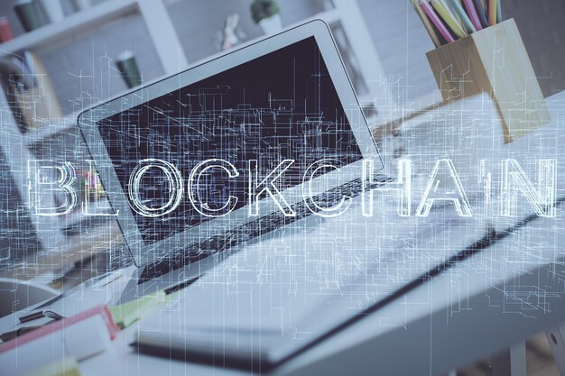 Exposición múltiple del holograma temático de blockchain y criptoeconomía y mesa con fondo de computadora Concepto de criptomoneda bitcoin