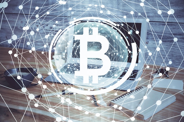 Exposición múltiple del holograma temático de blockchain y criptoeconomía y mesa con fondo de computadora Concepto de criptomoneda bitcoin