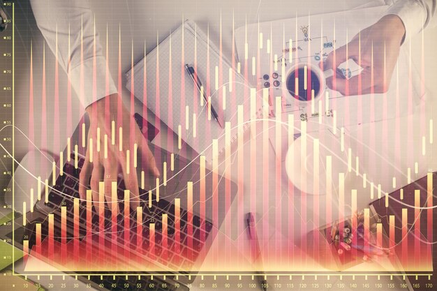 Exposición múltiple de las manos del hombre escribiendo en el teclado de la computadora y dibujo de hologramas de gráficos de divisas Vista superior Concepto de mercados financieros