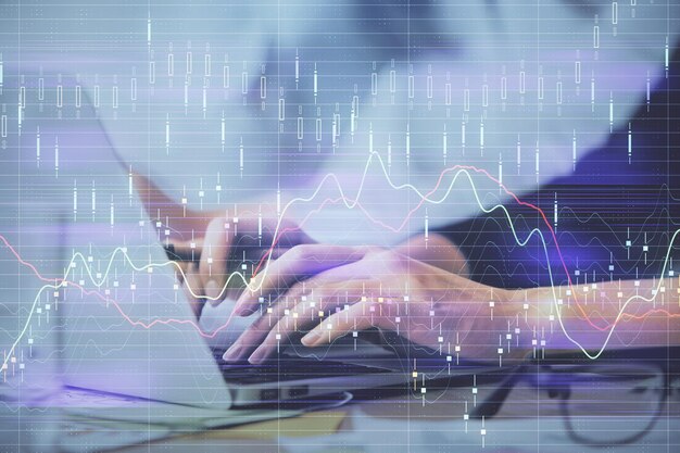 Exposición múltiple de manos de mujer escribiendo en computadora y gráfico financiero holograma dibujo concepto de análisis del mercado de valores