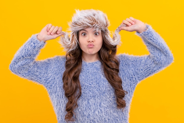 Expresar emoción positiva moda de invierno niño divertido con pelo rizado en sombrero con orejeras