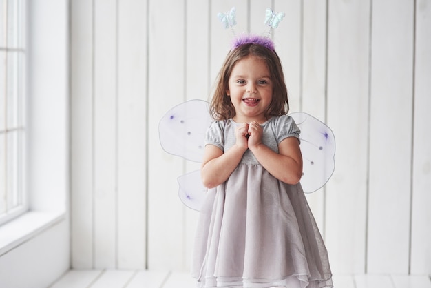 Expresión de espera por el regalo. Hermosa niña con traje de hadas divirtiéndose posando para las fotos.