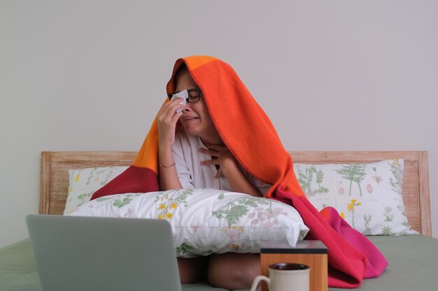 Expresión facial de una chica que se ve triste viendo el drama sola en su dormitorio usando una laptop