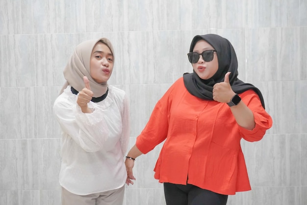 La expresión feliz de dos mujeres con hijab en ropa blanca y roja