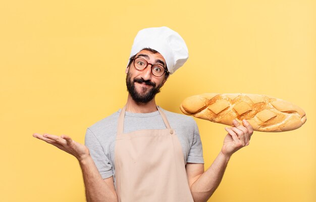 Expresión feliz del hombre joven del cocinero barbudo que sostiene un pan