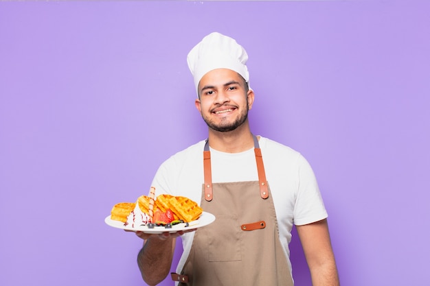 Expresión feliz joven hispano. chef con concepto de waffles