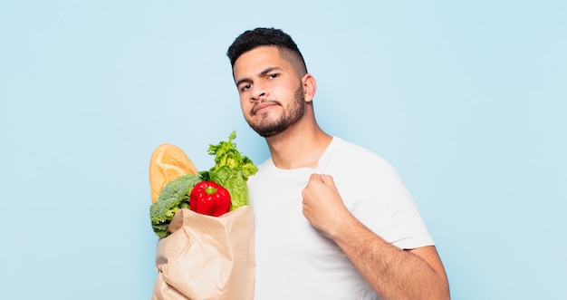 Expresión feliz joven hispano. concepto de compras de verduras