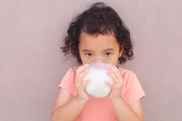 Expresión de una niña que bebe leche en un vaso