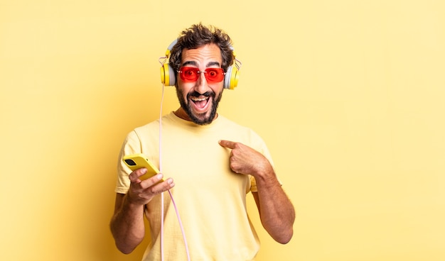 Expresivo loco sintiéndose feliz y apuntando a sí mismo con un emocionado con auriculares