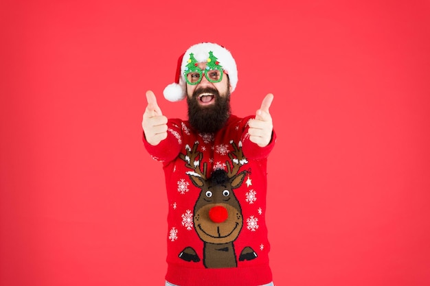 Express positivität frohe weihnachten hipster mann rentier auf strickpullover winterurlaub kalte saison kleidung frohes neues jahr weihnachtsmann party brille fröhlich weihnachtsmann daumen hoch beste weihnachten aller zeiten