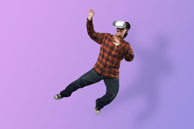 Expressão de homem asiático espantado usando fone de ouvido de vidro VR levitando no ar em bg roxo funky