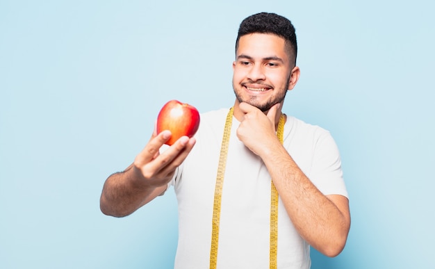 Expressão de pensamento jovem hispânico e segurando uma maçã. conceito de dieta