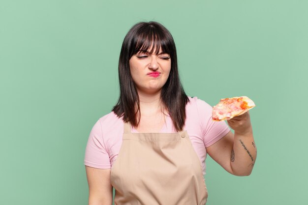 Expressão de raiva de mulher bonita chef e segurando uma pizza