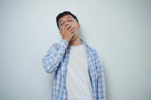 Expressão do rosto do homem asiático sentindo-se sonolento segurando a boca isolada no fundo branco