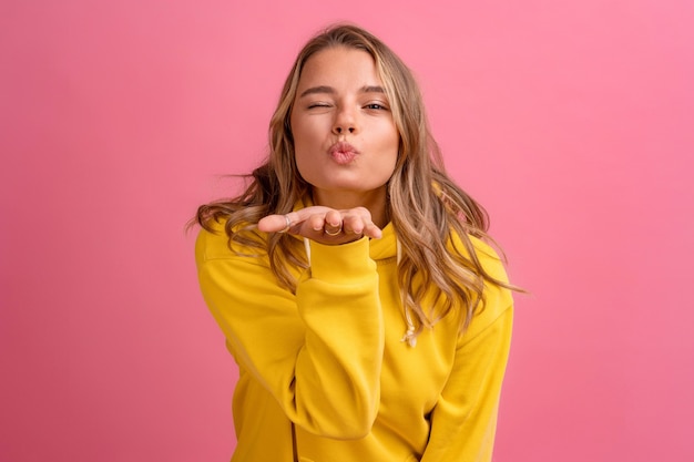 Expressão do rosto fofo de uma jovem mulher loira bonita posando com um capuz amarelo na rosa