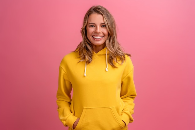 Expressão do rosto fofo de uma jovem mulher loira bonita posando com um capuz amarelo na rosa