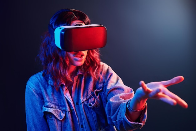 Expressão facial de jovem com óculos de realidade virtual na cabeça em neon vermelho e azul em estúdio