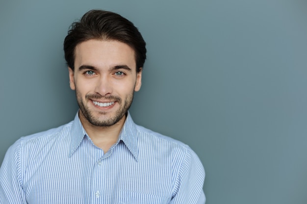 Expressão facial. Retrato de um homem alegre e simpático, morena, olhando para você enquanto mostra seu sorriso positivo