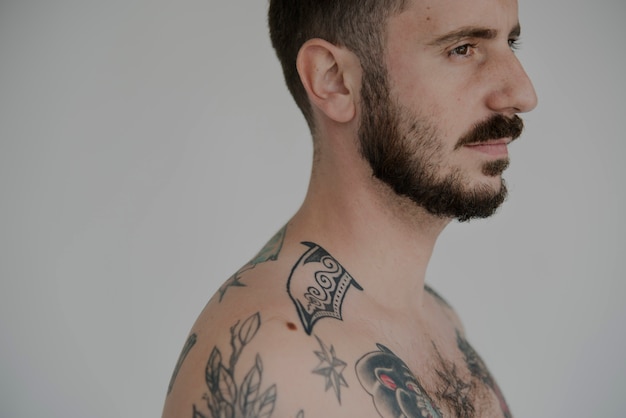 Expressão facial séria homem tatuado nu